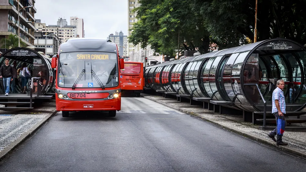 Ônibus vermelho do transporte coletivo de Curitiba parado junto às estações-tubo