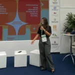 Fernanda Shulte, mulher branca e gerente de projetos da HOTMILK, apresenta o Paraná Festivais no Smart City